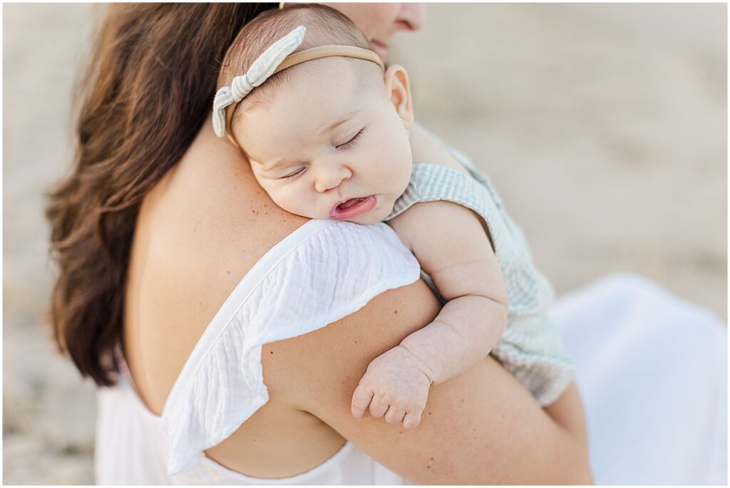 Baby sleeping on mom's shoulder in cape henlopen state park on the beach