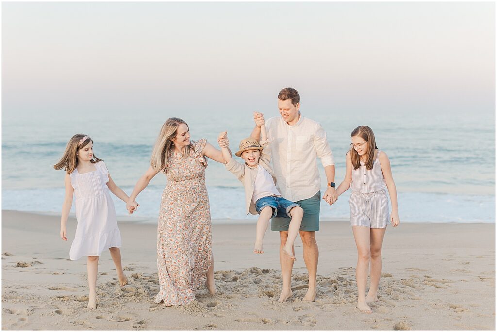 mom and dad swing their youngest son up in the air during their family session in rehoboth beach delaware