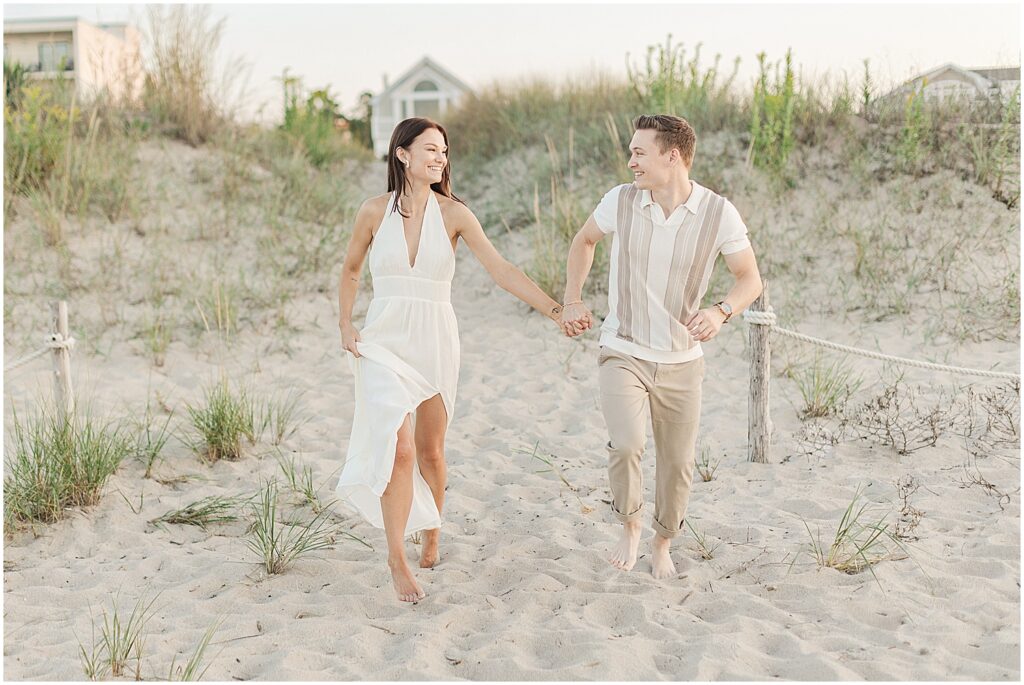 couple running towards their lewes beach engagement photographer